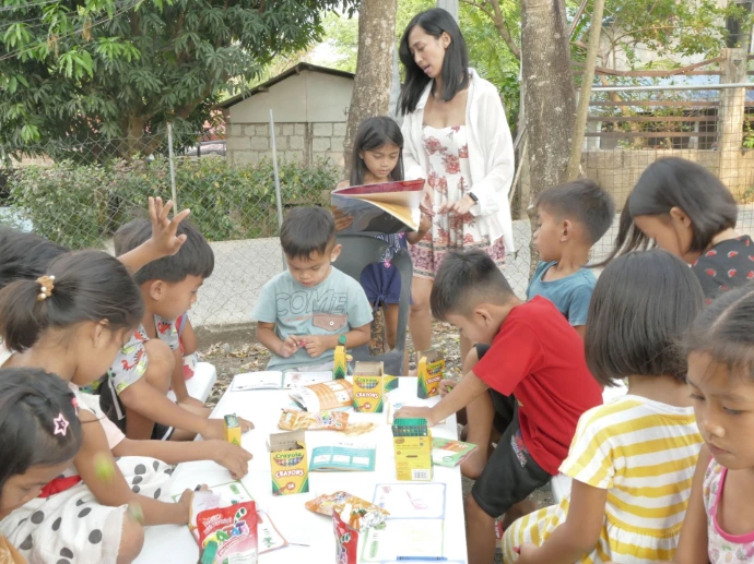 Mary Joy Olmstead encouraging a child to read in front of the class